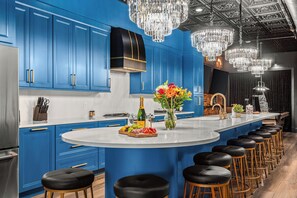 A modern kitchen with blue cabinets, a central island with stools, and a chandelier. - The Velvet Vault-Luxury Downtown loft with River View & walk to Broadway (Nashville)