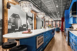 A modern kitchen with blue cabinets, a white countertop, and a bar area with stools.