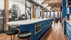 Una cocina moderna con armarios azules, una isla blanca y taburetes negros.
