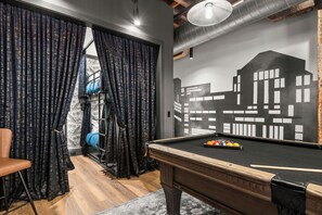 Ein Billardtisch mit Stadtbild-Wandgemälde, ein Sessel und ein Fenster mit Vorhängen.