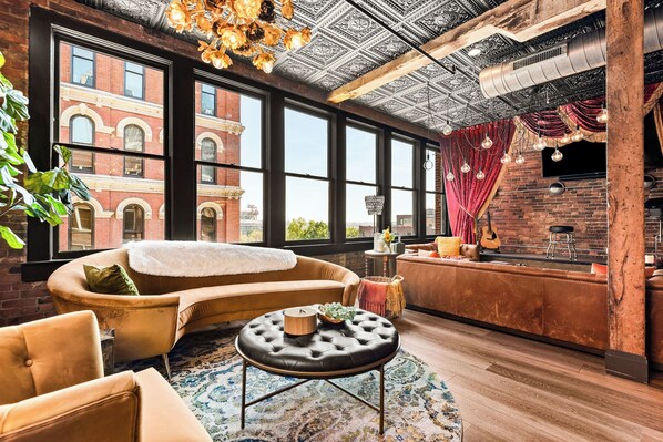 A cozy interior with a sofa, armchairs, a round coffee table, and a bar area with a guitar.