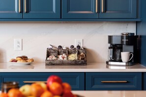 Eine Küche mit blauen Schränken, einer Kaffeemaschine und einer Obstschale.