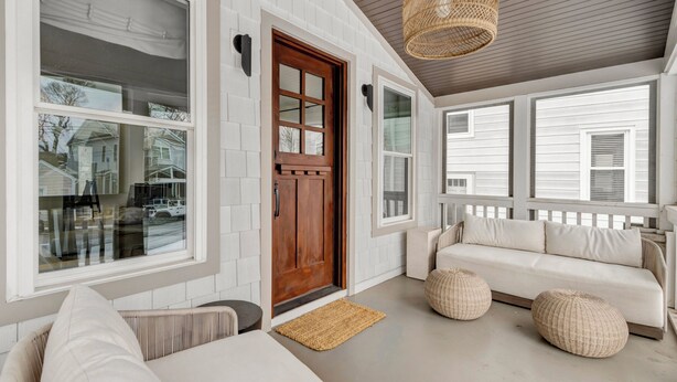A covered porch with a white exterior, a wooden door, and a beige sofa with cushions. - LARGE HOME, CLOSE TO THE BEACH! (REHOBOTH BEACH)