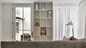 A living room with a grey sofa, a white shelving unit with decorative items, and a floor lamp. - LARGE HOME, CLOSE TO THE BEACH! (REHOBOTH BEACH)