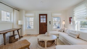 A living room with a wooden bench, a round table, a white sofa, and a door with a window. - LARGE HOME, CLOSE TO THE BEACH! (REHOBOTH BEACH)
