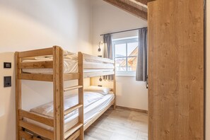 Habitación con literas, techo de madera y ventana con cortinas.