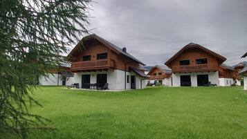 Een rij chalets met houten gevels en balkons, omringd door een verzorgd gazon.