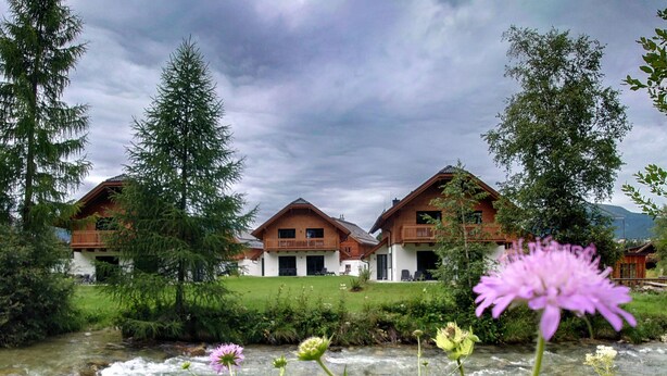 Ein Chalet mit einem klaren Bach davor.