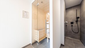 Ein modernes Badezimmer mit Holzauna, separater Duschkabine und Sauna mit Glastüren.