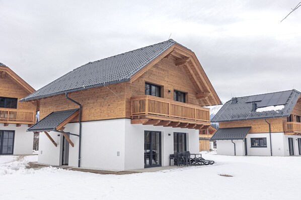 Una casa moderna de madera con balcón, garaje y zona de estar cubierta al aire libre.