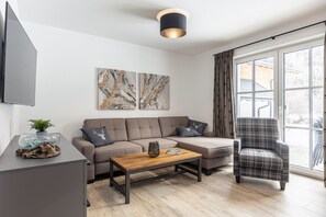 Un salon moderne avec un canapé, un fauteuil, une table basse et des œuvres d’art accrochées au mur.