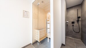 Un baño moderno con cabina de ducha de madera y zona de ducha separada con ducha de mano.