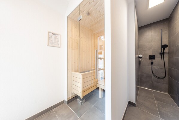 A modern bathroom with a wooden shower enclosure and a separate shower area with a handheld showerhead.