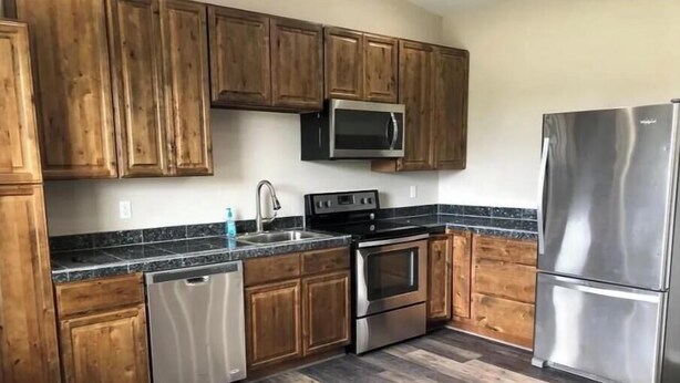 A kitchen with wooden cabinets, stainless steel appliances, and a granite countertop.