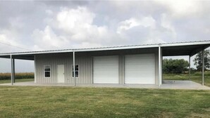 A single-story building with a covered porch and two garage doors.