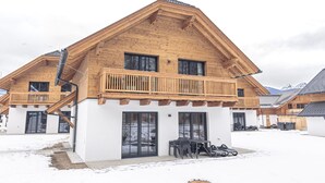 Un chalet en bois doté d’un balcon, de grandes fenêtres et situé à proximité d’un télésiège.