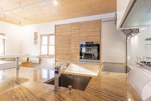 Une cuisine moderne avec un plafond en bois, un four encastré et un évier en acier inoxydable.
