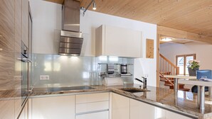 Een moderne keuken met roestvrijstalen apparatuur, een marmeren werkblad en een houten plafond.
