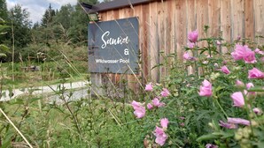 A wooden building with a sign that reads "Sahnd & Wildwasser Pool". - AlpiNest Apartment Samspitze 2 (Mariapfarr)