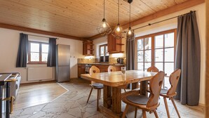A spacious kitchen with a large wooden table and chairs, stone flooring, and wooden ceiling beams. - AlpiNest Apartment Samspitze 2 (Mariapfarr)