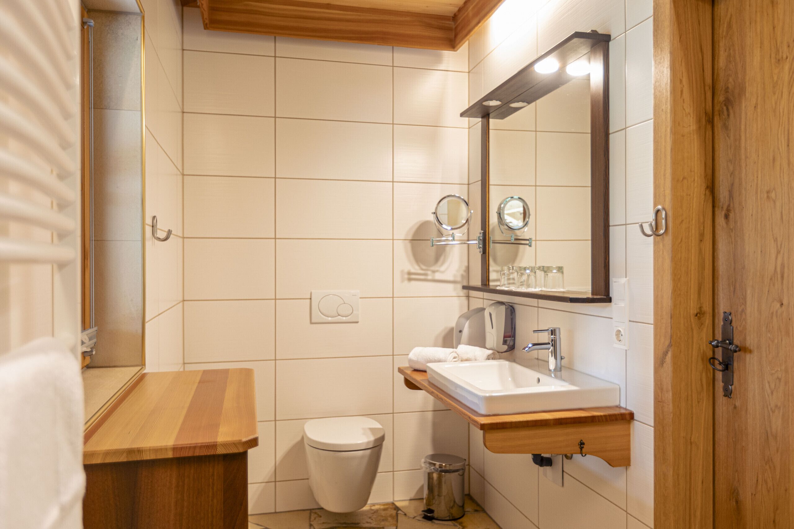A bathroom with a wooden vanity, a white sink, a mirror, and a toilet.