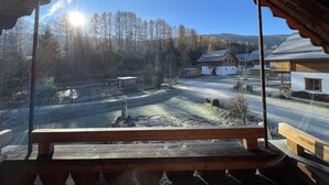 Un banco de madera con vistas a un paisaje rural, cielo despejado y una vista de casas y árboles.