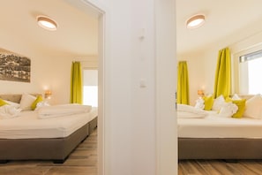 A hotel room with two beds, a large window with curtains, and a painting on the wall. - Chalet Almrose Zell am See (Zell am See)