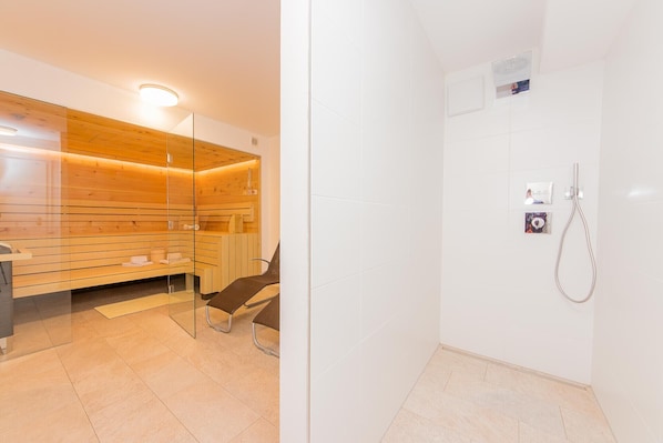 A modern bathroom with a sauna, a shower area, and a glass partition. - Chalet Almrose Zell am See (Zell am See)
