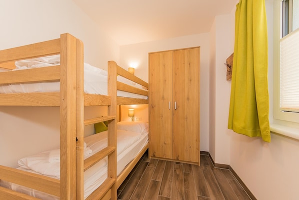 Habitación con literas, un armario de madera y una ventana con cortinas.