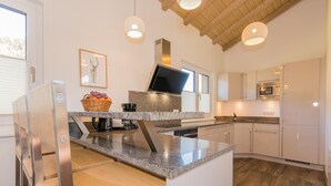 A modern kitchen with granite countertops, stainless steel appliances, and a wooden ceiling. - Chalet Almrose Zell am See (Zell am See)