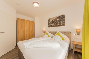 Una habitación de hotel con cama, armario de madera y un cuadro en la pared.