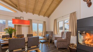 Comedor con mesa y sillas, chimenea y vista al exterior.