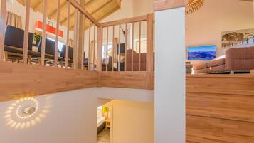 A wooden staircase with a white wall and a television in the background.