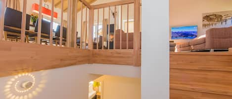 A wooden staircase with a white wall and a television in the background.
