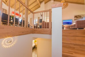 Un escalier en bois, avec un mur blanc et un luminaire au plafond.