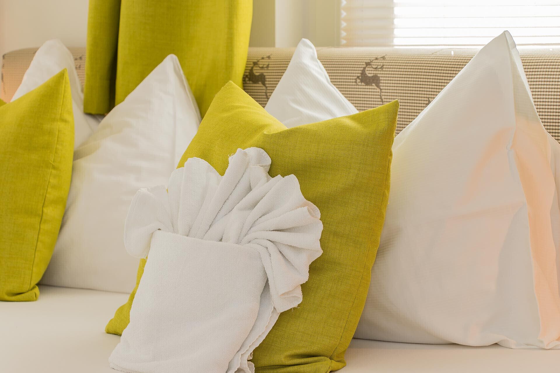 A row of pillows on a sofa with a white towel draped over one.