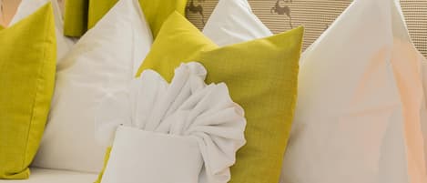 A row of pillows on a sofa with a white towel draped over one.