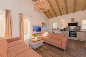 A spacious living area with a sofa set, a dining table, and a kitchen area with a TV and oven.