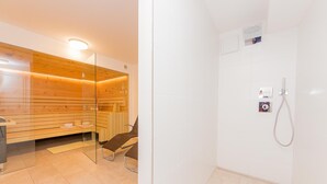 Een moderne badkamer met een sauna, een douche en een glazen scheidingswand.