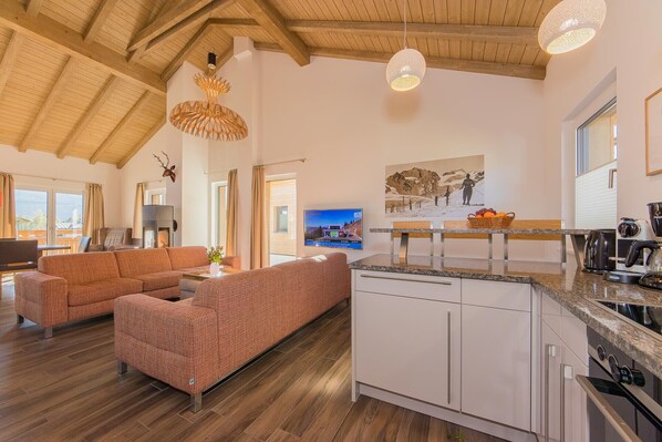 Amplia sala de estar con un conjunto de sofás, una cocina con encimera de granito y un comedor con mesa y sillas.