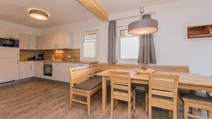 Eine moderne Küche mit Holzschränken, einem Esstisch mit Stühlen und einer Pendelleuchte.
