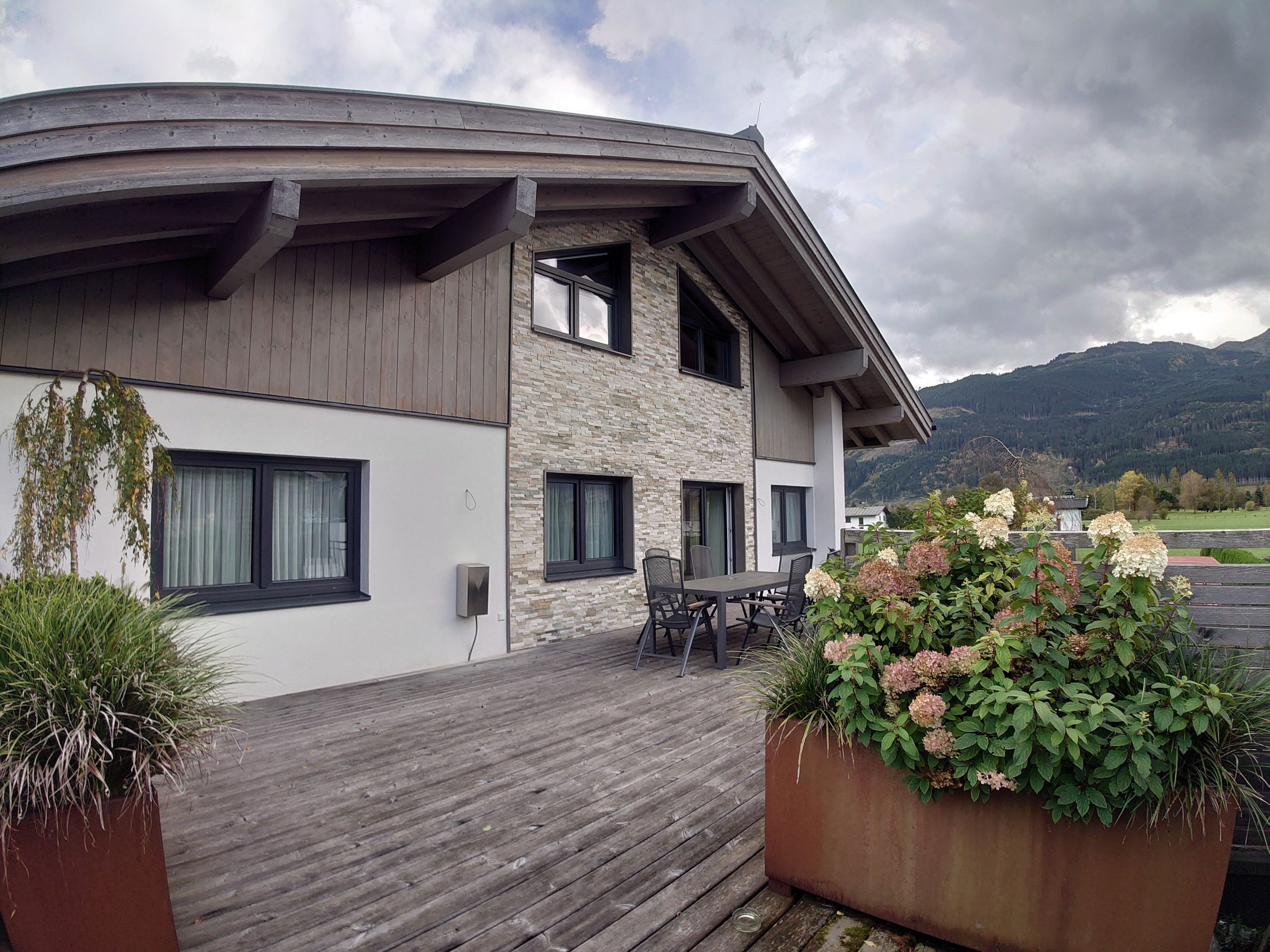A modern two-story building with a wooden deck and outdoor seating area.