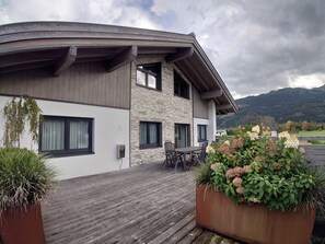 A modern two-story building with a wooden deck and outdoor seating area. - Kitzview Terrace Apartment (Zell am See)