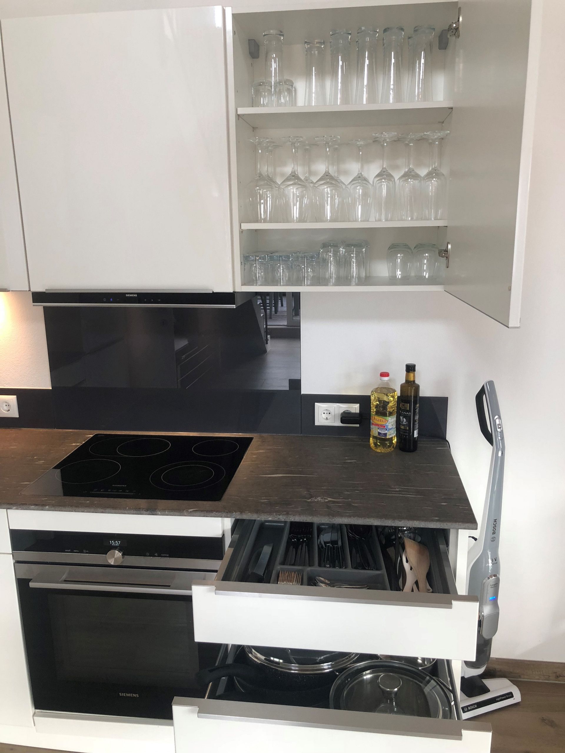 Una cocina equipada con lavavajillas, horno, microondas, placa de inducción y cafetera Siemens.