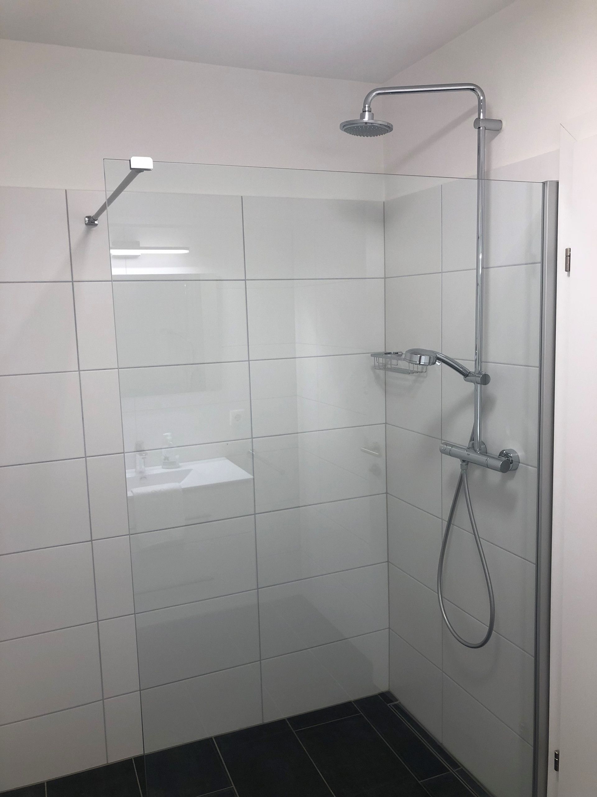 Eine Dusche mit Handbrause und am Wand montiertem Wasserhahn.