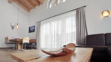 Un salon moderne avec une table basse en bois, un canapé en cuir et un coin repas comprenant une table et des chaises en bois.