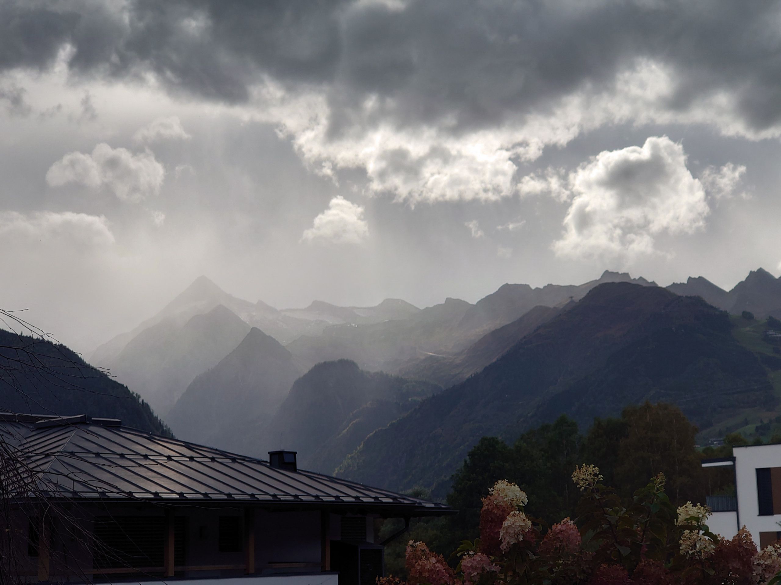 Un paysage montagneux avec une maison dotée d’un toit en pente et d’une petite dépendance attenante.