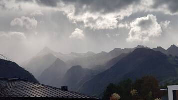 Eine gebirgige Landschaft mit einem Haus, das ein geneigtes Dach und einen kleinen Anbau hat.