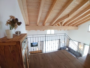 En trætrap med gelænder i metal, der fører op til en balkon med udsigt over landskabet.