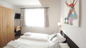 A bedroom with a bed, a wooden wardrobe, a TV, and a painting on the wall. - Kitzview Terrace Apartment (Zell am See)